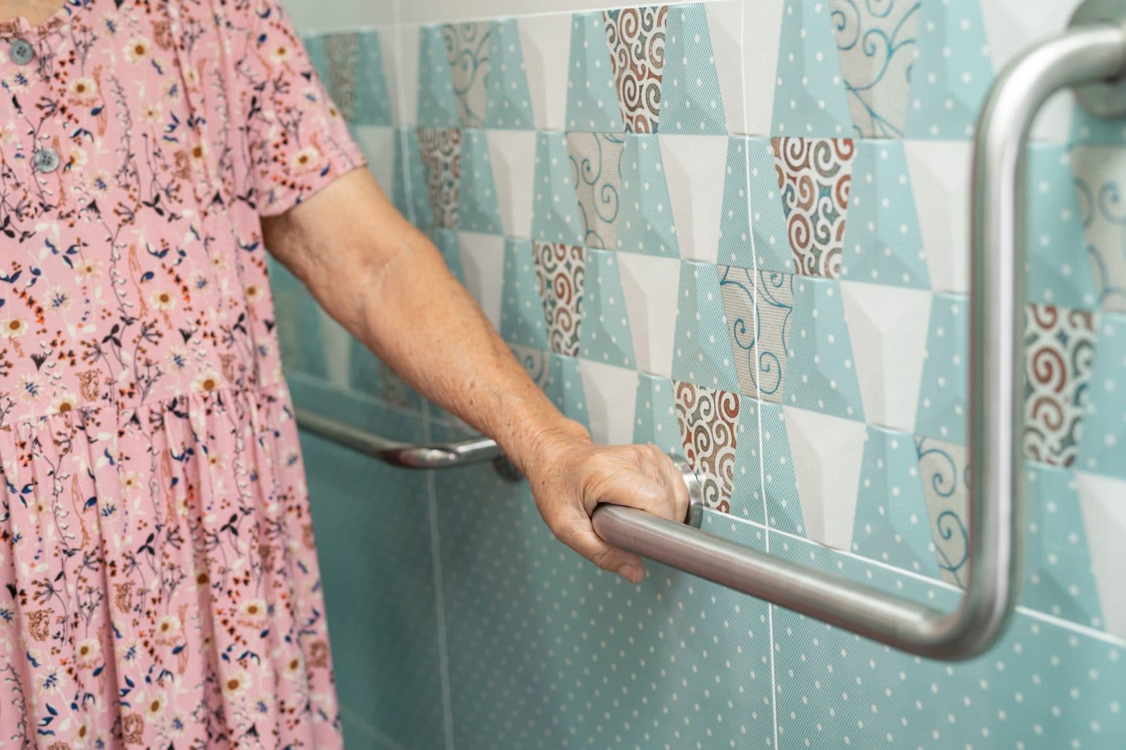 Persona mayor apoyándose en la barra de sujeción del baño