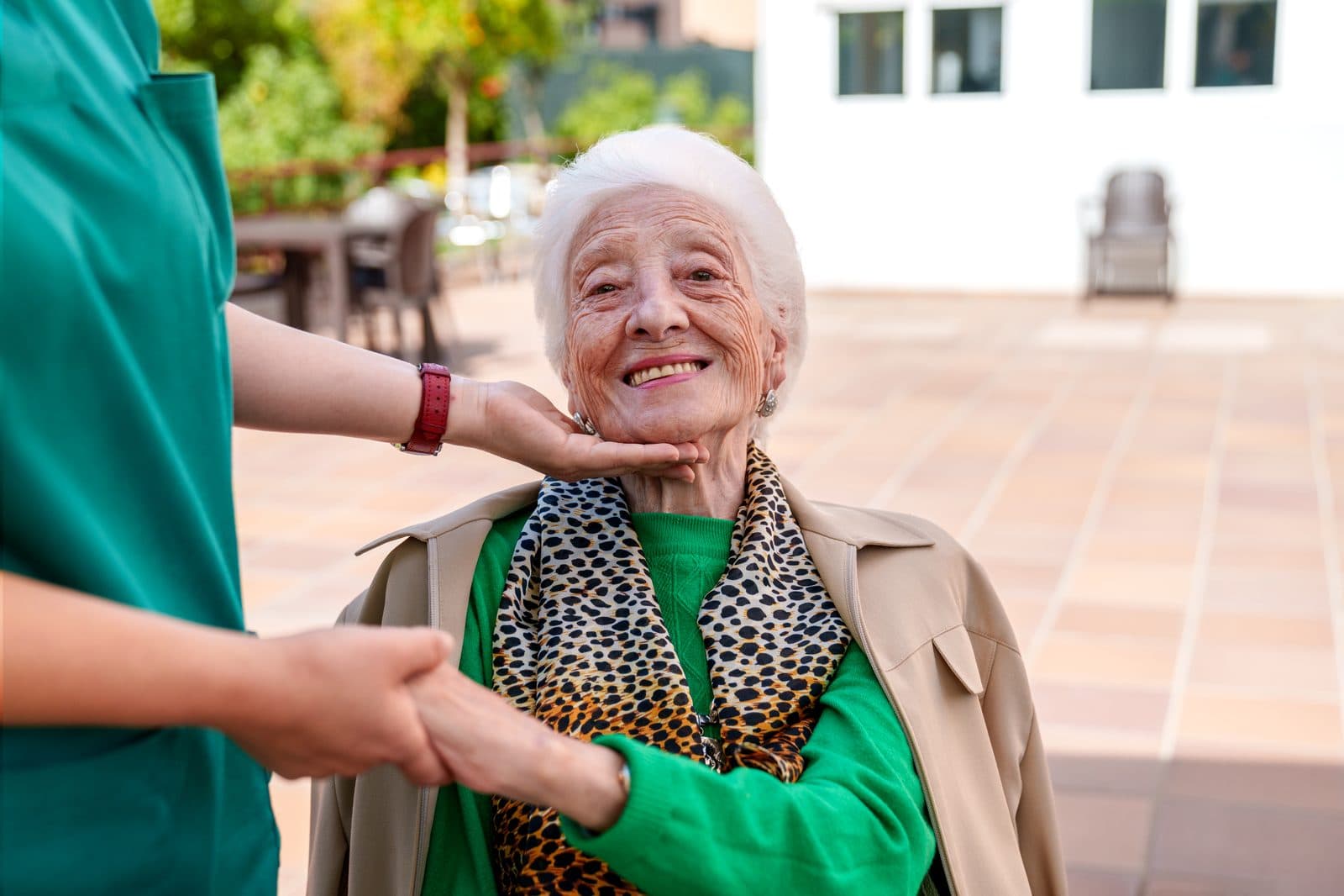 Cuidadora dando la mano a una señora mayor sonriente en el jardín