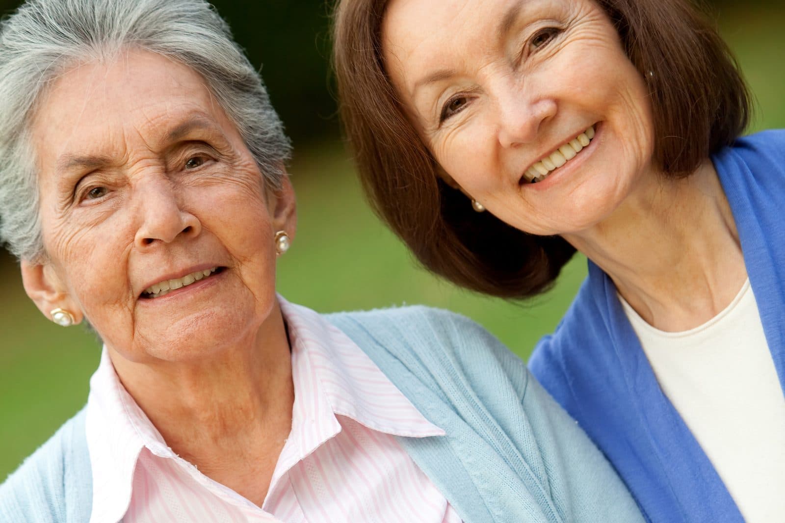 Dos señoras mayores sonriendo juntas al aire libre