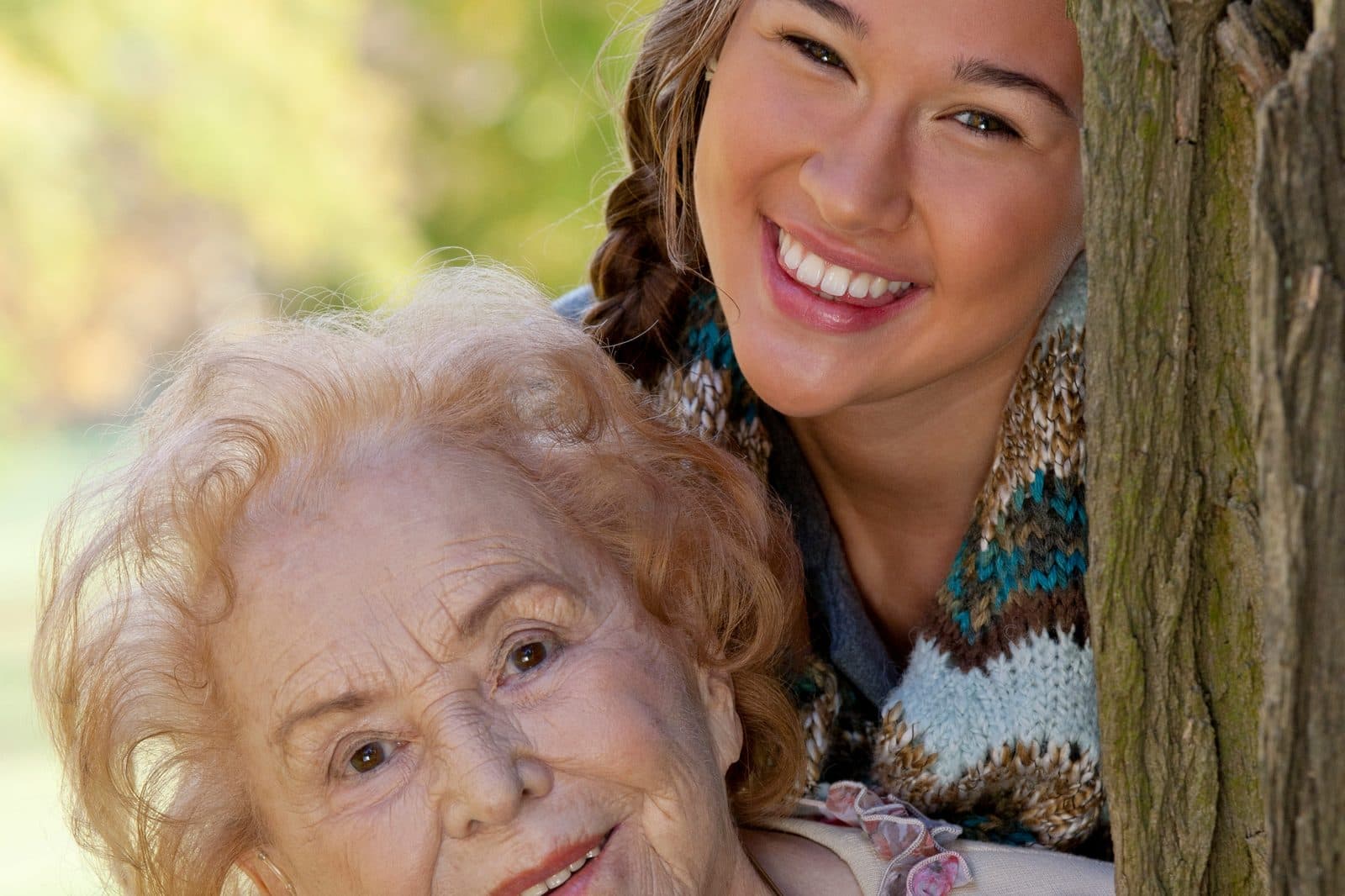 Señora mayor sonriendo junto a su nieta en el parque