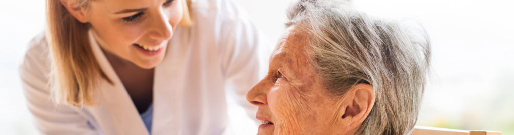 Cuidadora y persona mayor disfrutando de una charla en el jardín.